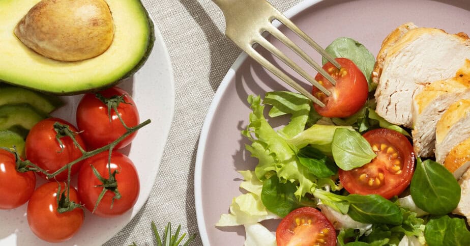 Talíř se zdravými potravinami vhodnými pro protikvasinkovou dietu, včetně avokáda, rajčat, listového salátu a kuřecího masa.